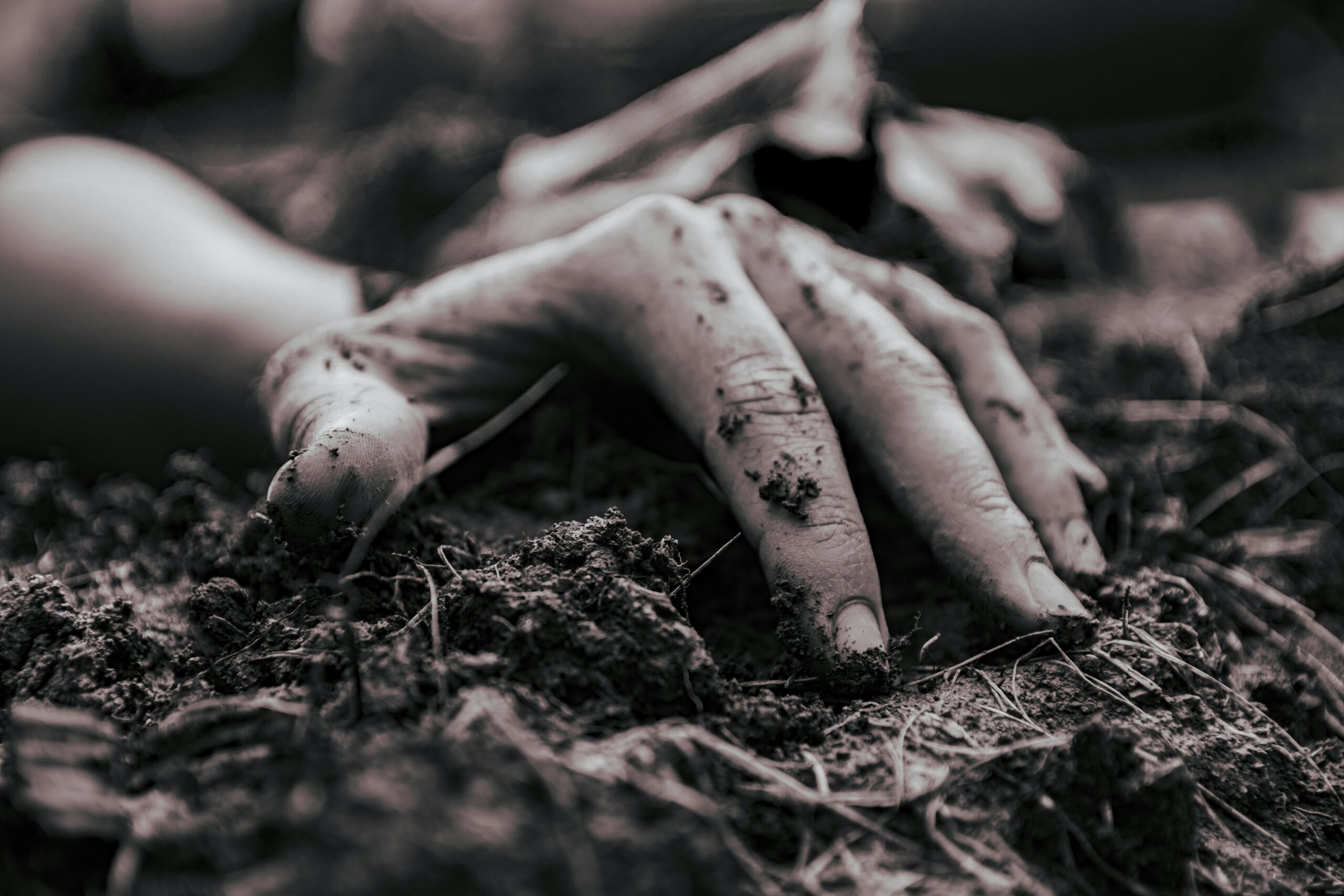 A hand reaching up from soil, representing emotional suppression, survival exhaustion, and the buried self ready to return.
