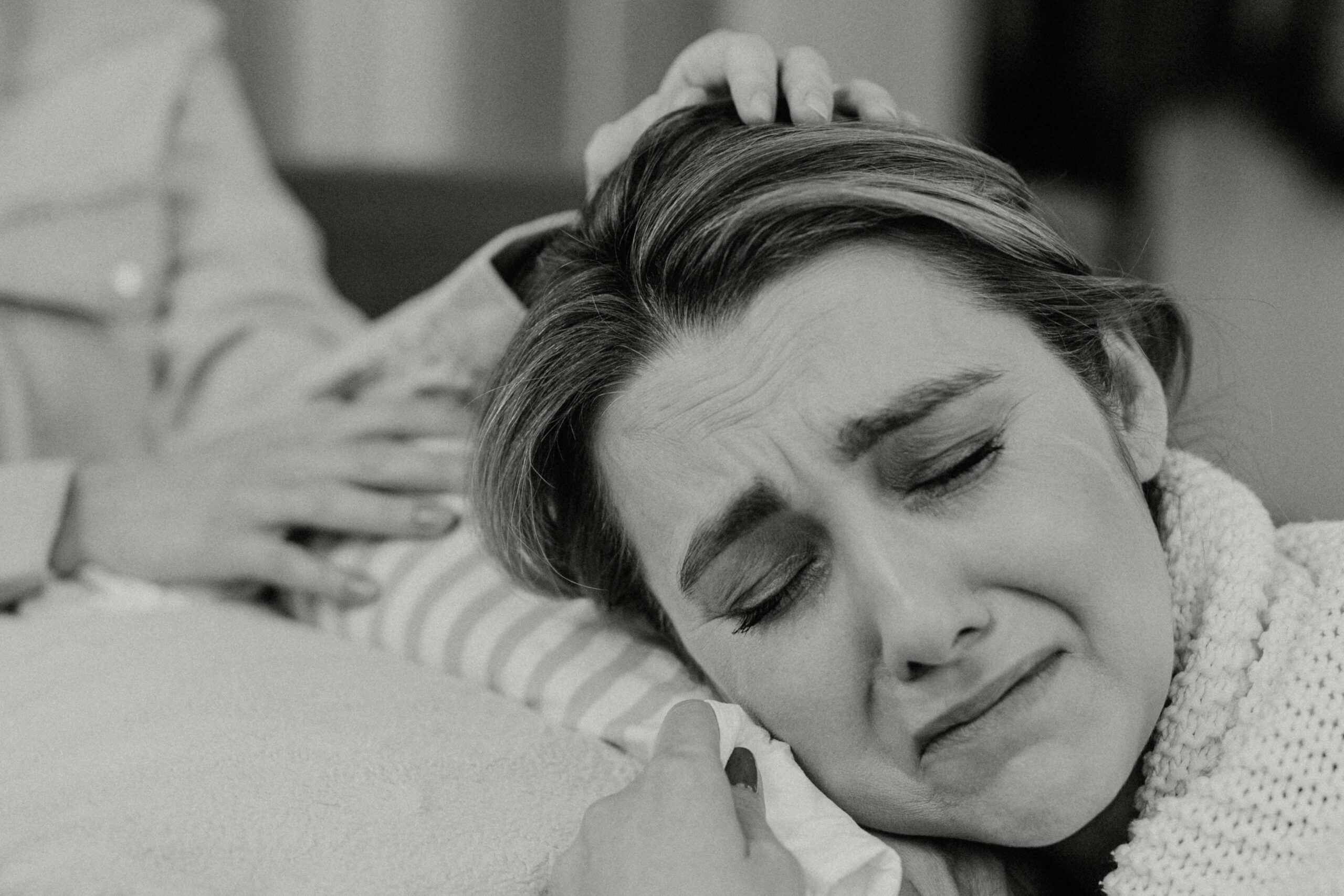 Woman crying while being comforted, symbolizing unspoken grief, nervous system release, and trauma healing.