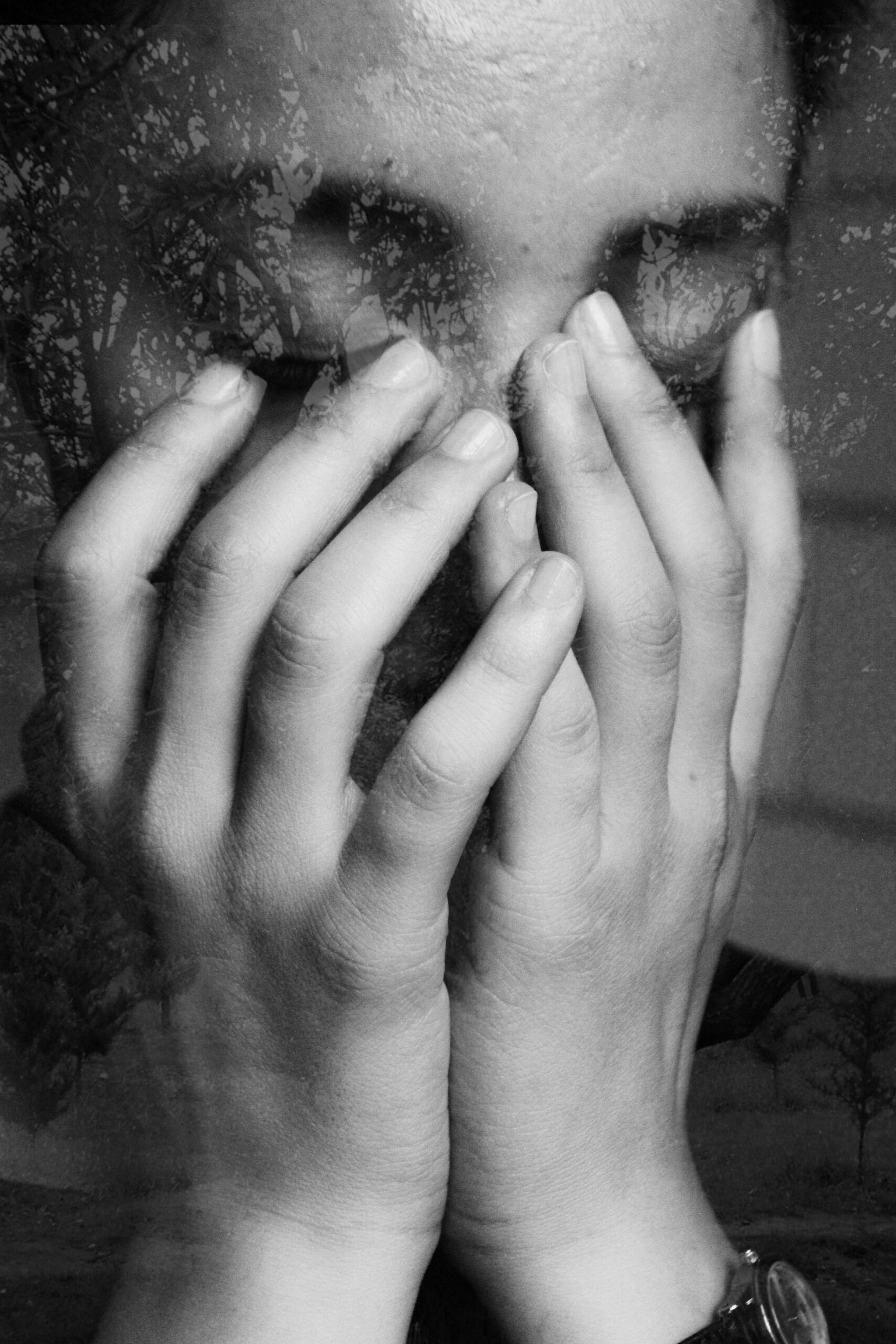 black and white image of woman with hands over her face representing voice suppression and silencing yourself