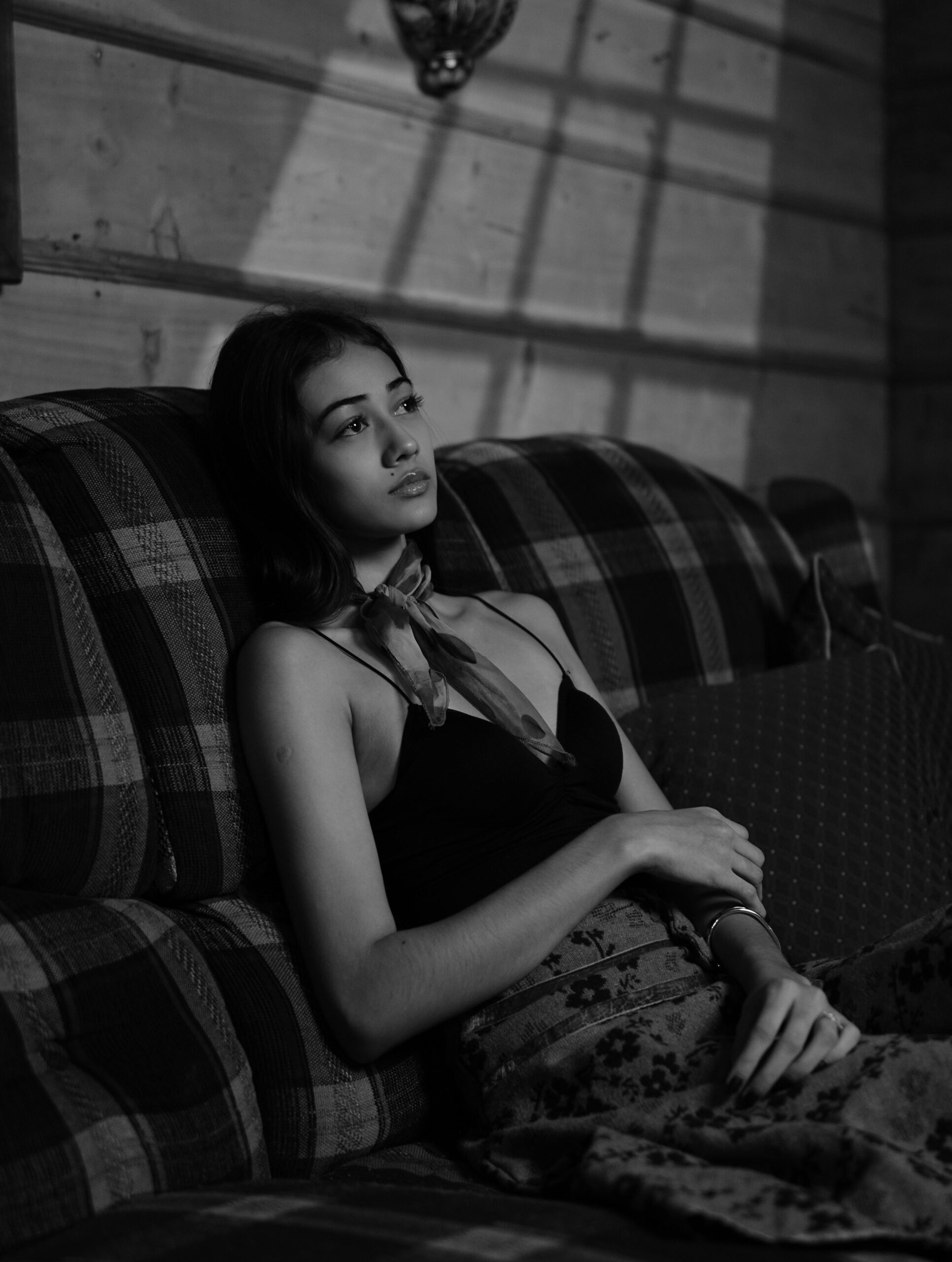 woman sat on sofa in black and white looking exhausted from carrying the emotional load in relationship