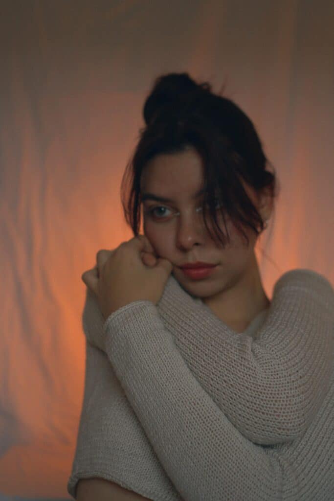 woman hugging herself in soft lighting, representing emotional shutdown